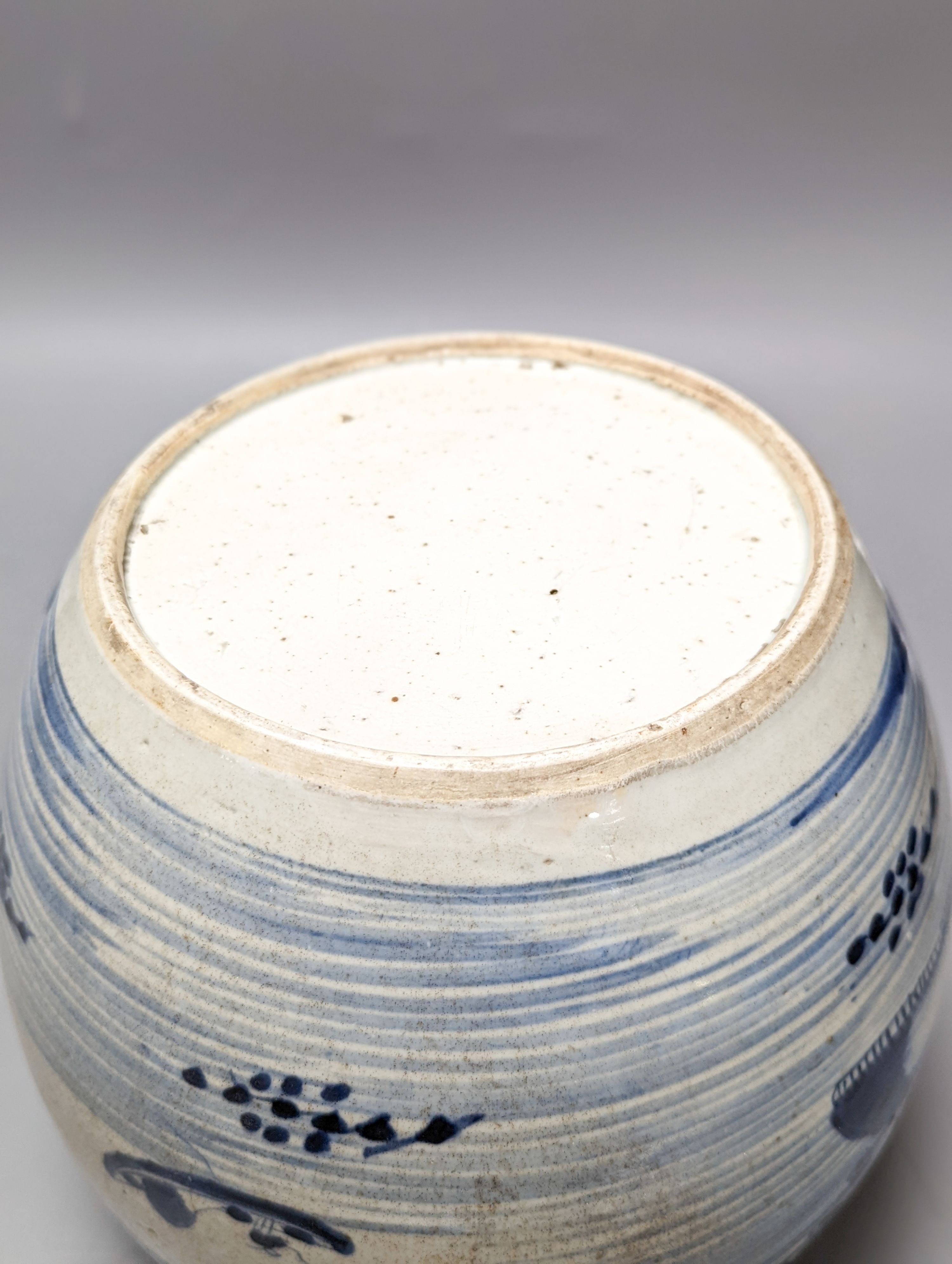 An 18th century Chinese provincial blue and white jar on a wooden stand. 25cm including stand